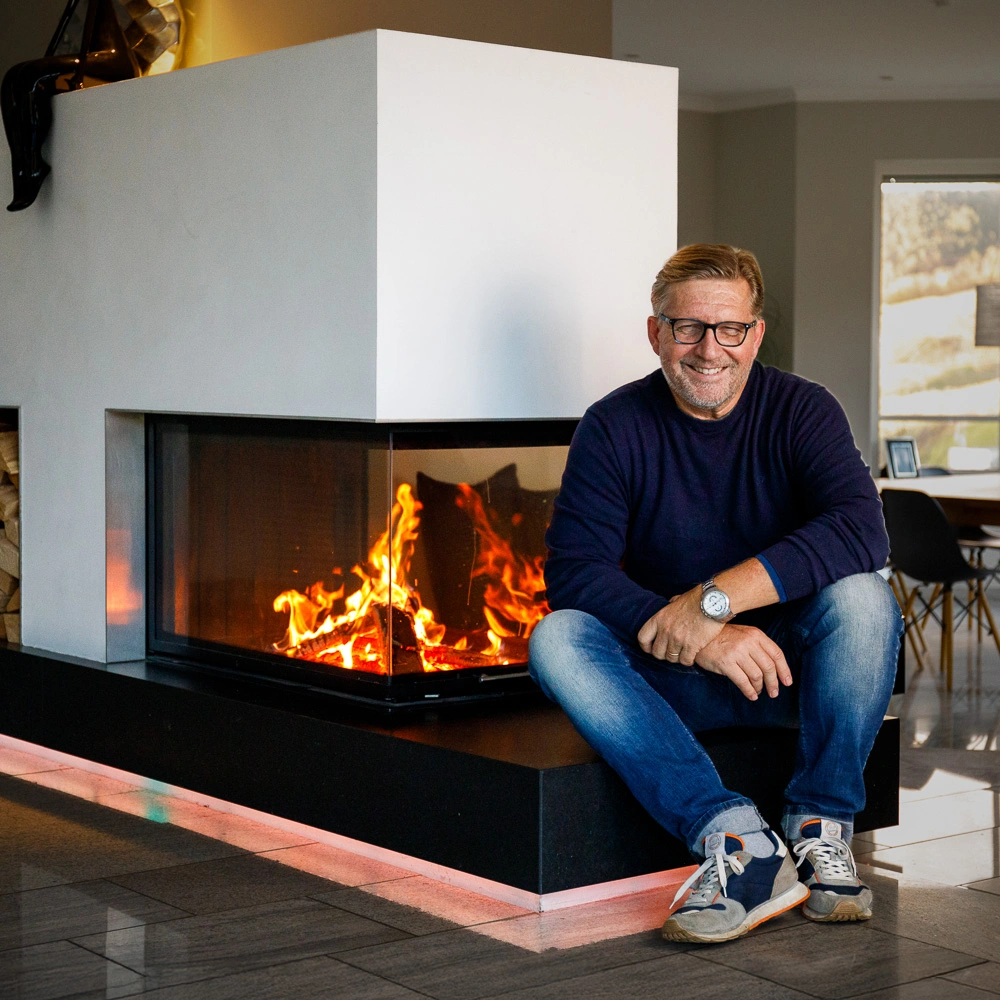 Holger Haas sitzend vor einem brennenden Designkamin