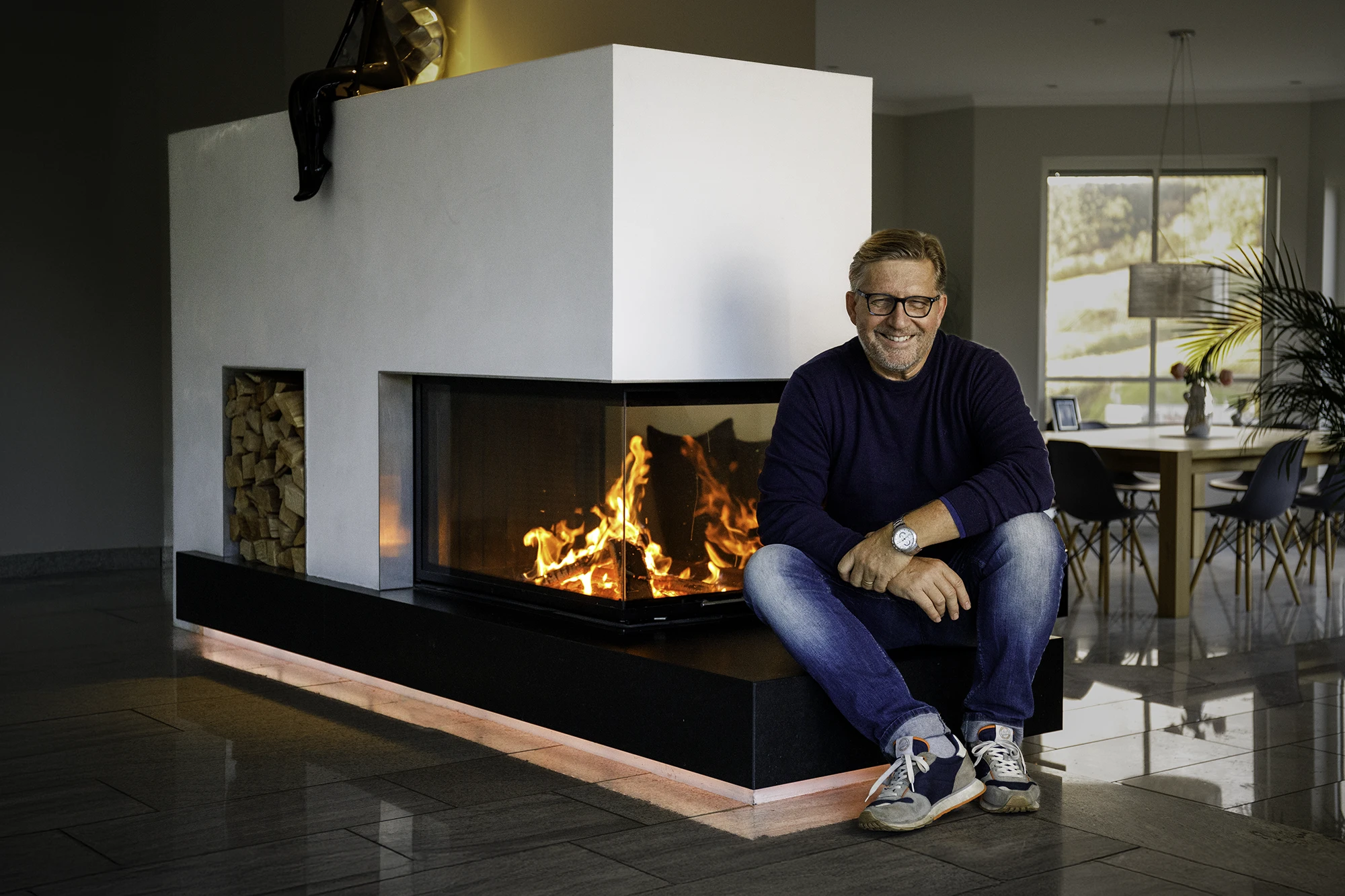 Holger Haas sitzend vor einem brennenden Designkamin